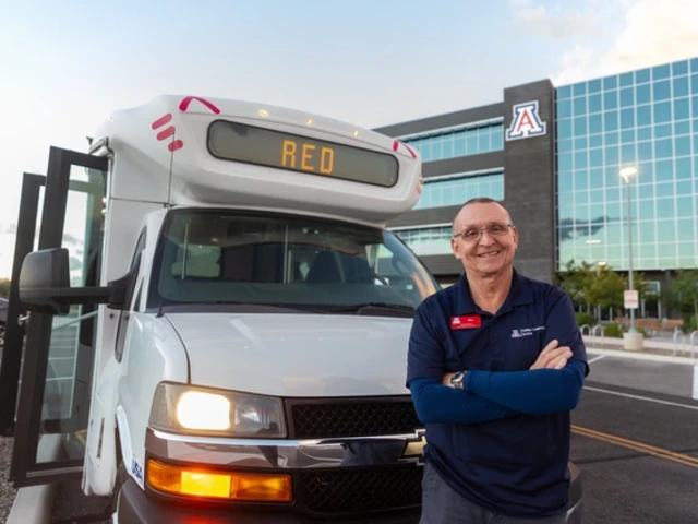 Bill Mason standing outside a Cat Tran shuttle near a building in the background with a Block A logo on it