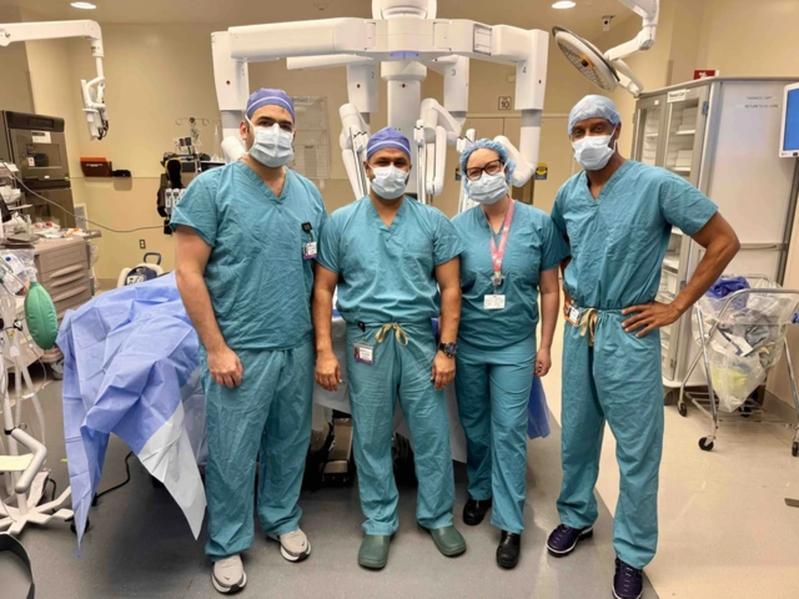 Doctors stand next to a machine in an operating room