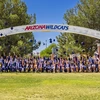 Several college students throw their caps into the air under an archway with the words Arizona Wildcats on it.