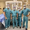Doctors stand next to a machine in an operating room