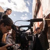 Film students surround a camera and film a scene outside of a restaurant.